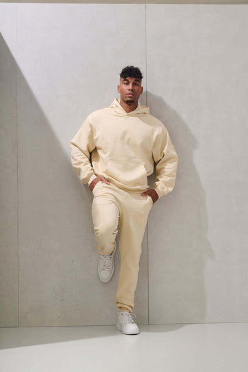 Man wearing beige oversized hoodie with matching cream joggers, full body front view - KAVEON