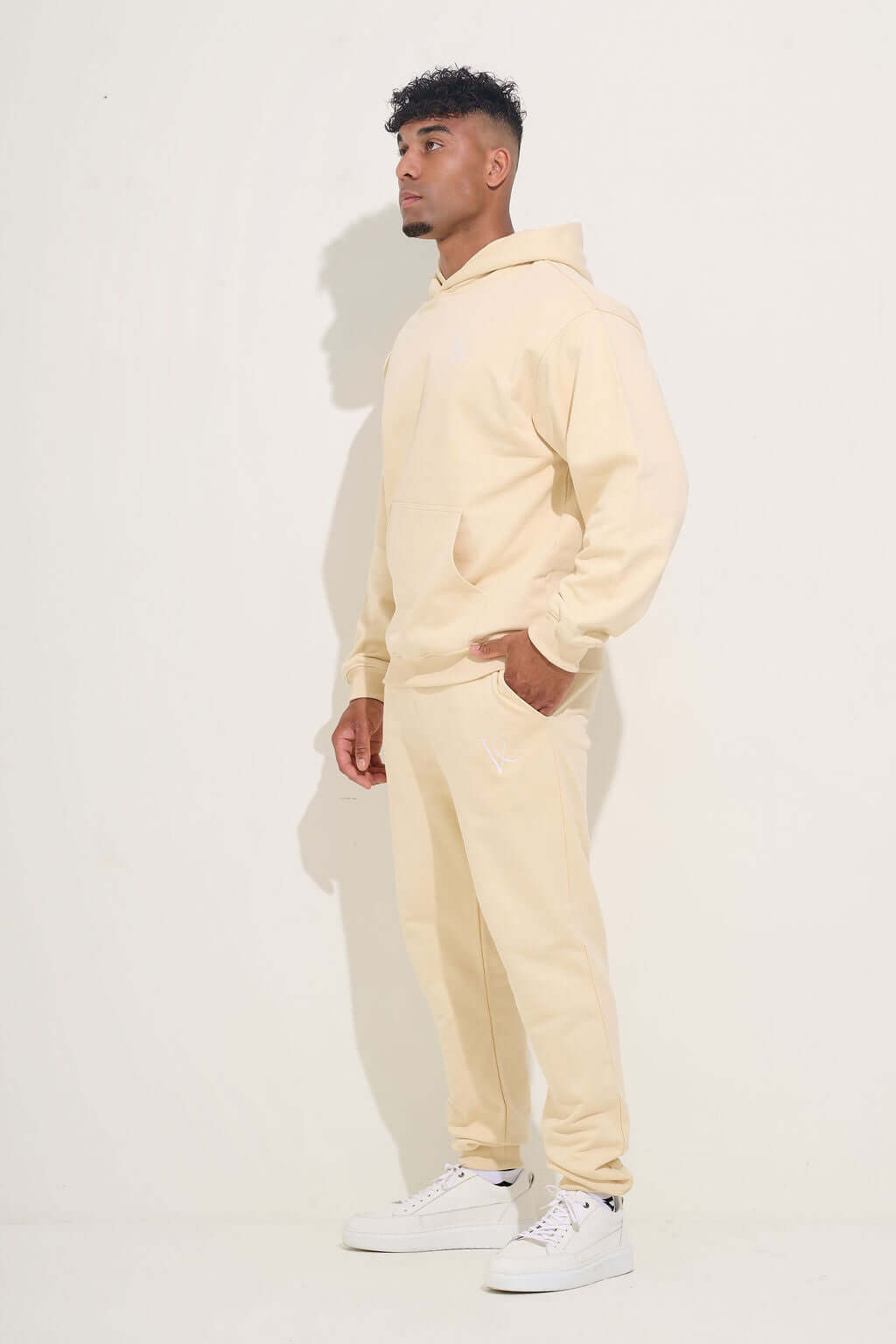 Side view of the cream hoodie and jogger set with white trainers - KAVEON